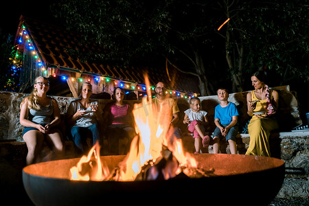 坐在火炉前举行烧烤派对的家庭