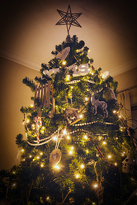 舒适的现代家居中的圣诞树装饰，闪烁着灯光和圣诞装饰品，顶部背景上有大星星
