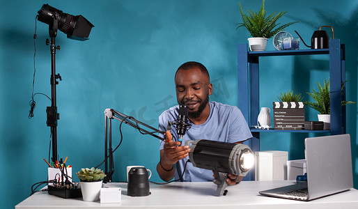 非洲裔美国视频博主的肖像，看着坐在视频博客工作室办公桌前的新型视频灯
