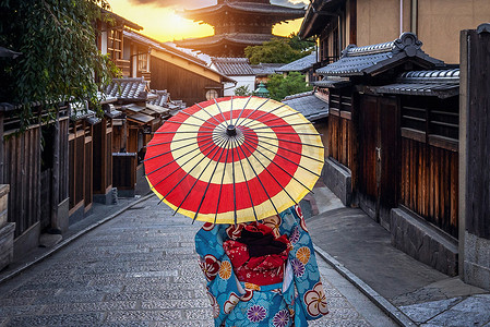 日本京都八坂塔和三年坂街穿着日本传统和服、带伞的女子。