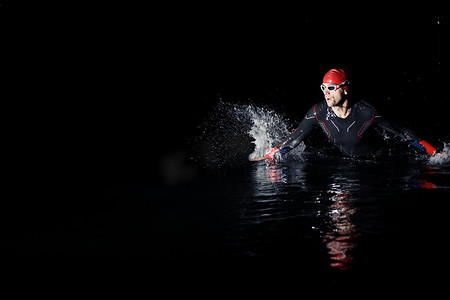 铁人三项运动员在黑夜完成游泳训练
