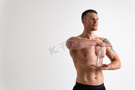 男性饮水健身用白色背景上的毛巾抽水，孤立强壮的肌肉训练男瓶男，肌肉运动。