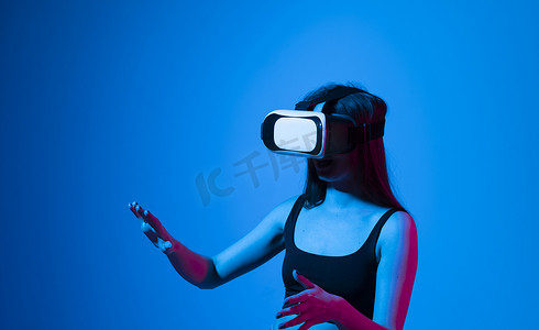 比划手摄影照片_微笑快乐的女人获得使用虚拟现实 vr 耳机眼镜的经验，在灰色背景上比划手。