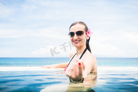 南海诸岛摄影照片_在无边泳池边缘做求爱手势的女人