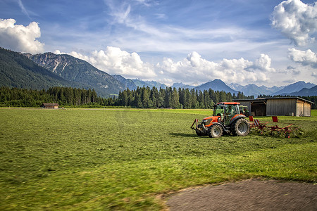 农业机械，拖拉机在蓝天的映衬下在田野里收草。