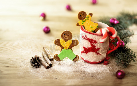 男人形状摄影照片_圣诞杯，上面有圣诞装饰品和木制背景中男人形状的饼干