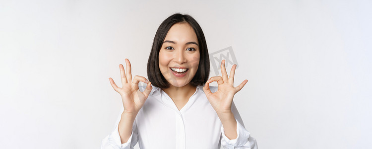 漫画头像女生摄影照片_特写亚洲女孩的头像，表现出好的、好的手势和满意的微笑、推荐、高兴、赞美和恭维，白色背景