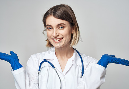 一位身穿医用长袍、戴着蓝色手套的护士用脖子上的听诊器做手势