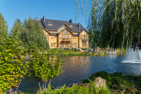 从绿色的柳枝后面到池塘和透明玻璃的房子，可以看到公园的美景