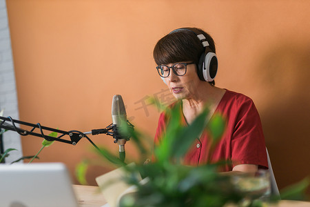 中年女电台主持人对着麦克风讲话和阅读新闻 — 电台广播在线概念