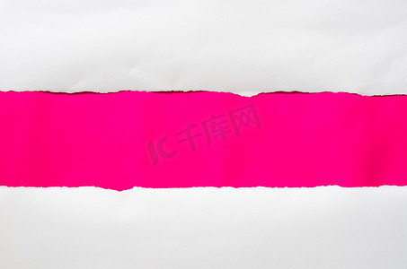 这张纸在粉红色的背景上被撕破，并且有一个切口