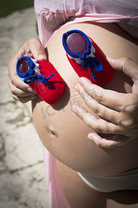 卡通短靴摄影照片_有红色和蓝色短靴的七个月孕妇
