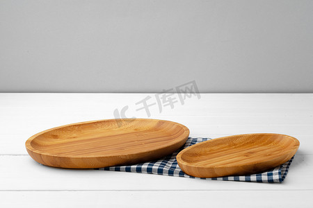 白色盘子摄影照片_白色木桌上棉餐巾上的木切板