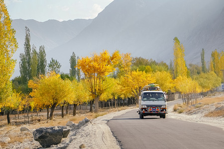 秋季，一辆当地巴士在山脉的铺砌道路上行驶