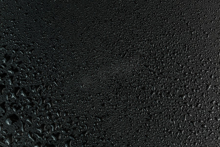 平坦的黑色橡胶表面宏观背景上的水滴