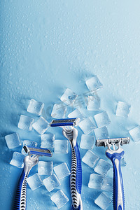 冷淡摄影照片_冷淡的蓝色背景上的三台剃须机加冰。