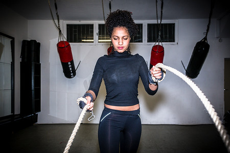 年轻健康的女性在功能训练期间用战绳锻炼