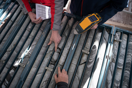 钻孔摄影照片_测量钻孔岩芯的采矿工人团队