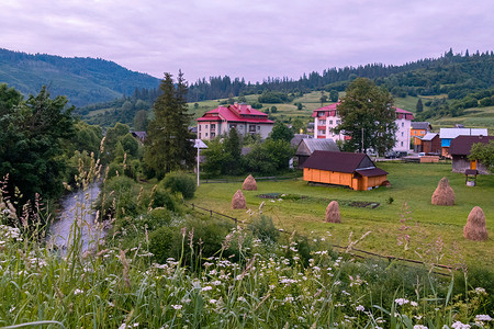 青山背景下小河道附近的红色屋顶和庭院的高层住宅楼