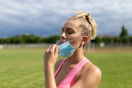 女性在户外训练或跑步后摘下医用口罩