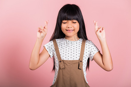 亚洲小孩 10 岁微笑交叉手指闭上眼睛