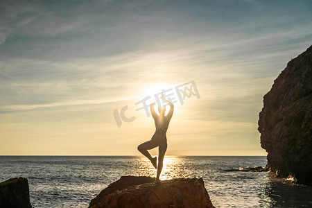 女子体操运动员正在海边夕阳的沙滩上训练。