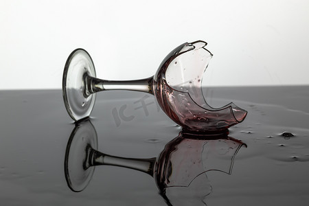 破碎的酒杯，上面有红酒，躺在湿的表面上
