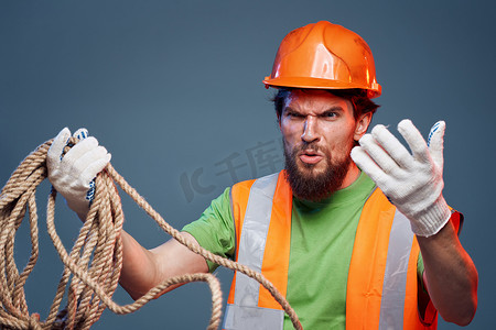辛勤的手摄影照片_身穿工作制服橙色漆绳的男子手握辛勤工作的裁剪视图
