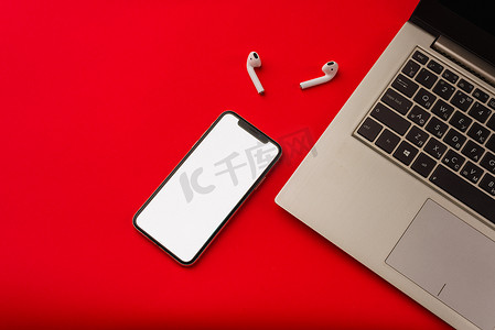 苹果x摄影照片_俄罗斯图拉 — 2019 年 5 月 24 日：红色背景中的苹果 iphone X 和 Airpods，带笔记本。