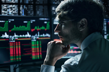 深思熟虑的投资者正在查看带有股市数据的监视器。