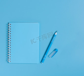 钢笔样机摄影照片_蓝色笔记本和钢笔套装在蓝色桌面背景上，顶部 vie