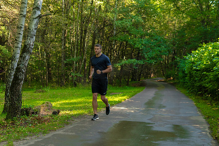 一名男子运动员在户外的公园里跑步，在森林周围，橡树绿草年轻持久的运动员跑步运动自然，生活方式慢跑者耐力人。