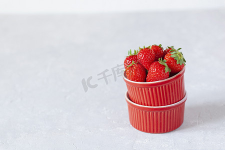 装满新鲜草莓的红碗，侧视图，灰色背景
