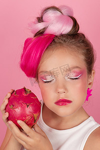 可爱的女孩在她的脸附近拿着一个火龙果。