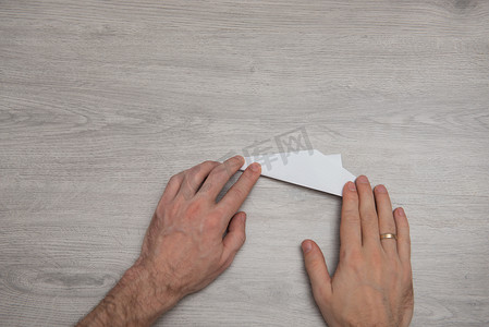 纸飞摄影照片_如何在带手臂的木桌上制作折纸纸飞机一步一步的照片说明。