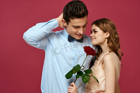 浪漫情侣的肖像，在孤立的背景和经典的西装晚礼服上爱上了红玫瑰