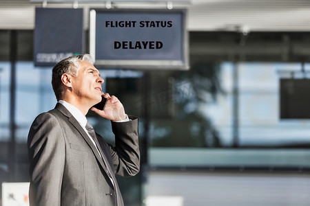 成熟的商人站在机场登机口报告航班延误情况
