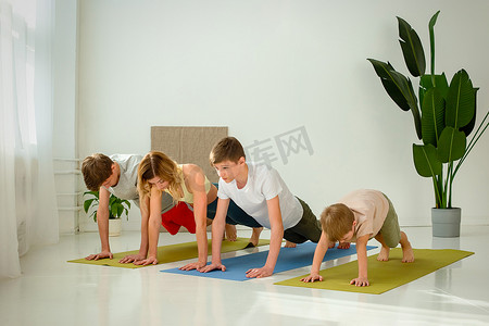 一个男孩、两个青少年和女人在垫子上做瑜伽练习