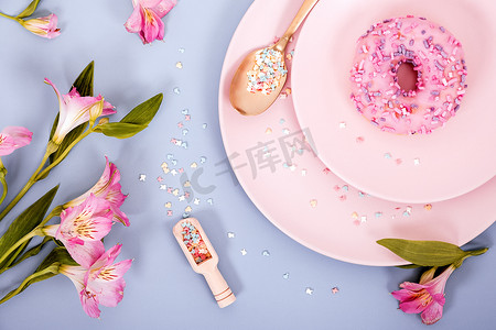 由盘子、甜甜圈、鲜花组成的柔和粉色和蓝色的组合