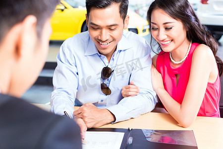 亚洲夫妇在经销商处签订汽车销售合同