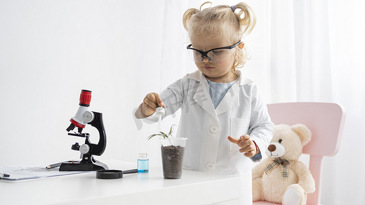 水果蔬菜学习摄影照片_正面图可爱的蹒跚学步的孩子用植物显微镜学习科学
