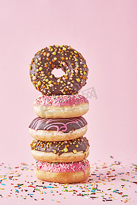 一堆装饰在粉红色背景上的彩色甜甜圈
