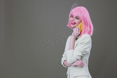 开朗的女人粉红色假发打电话