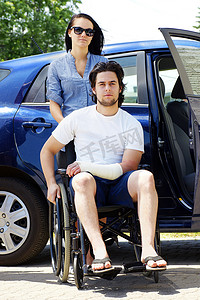 受伤女孩摄影照片_年轻夫妇与坐在轮椅上的男人