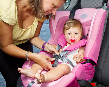 女人将儿子固定在汽车婴儿座椅上