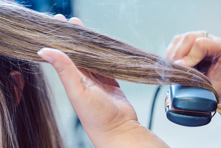 扁平化的ppt摄影照片_美发师在女性顾客的头发上使用扁铁