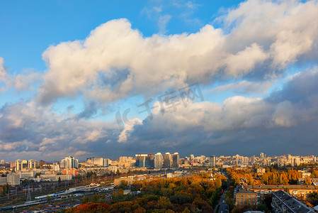 秋天基辅多彩的城市景观，灰色云层后面的阳光捕捉并照亮了城市公园的橙色树叶。