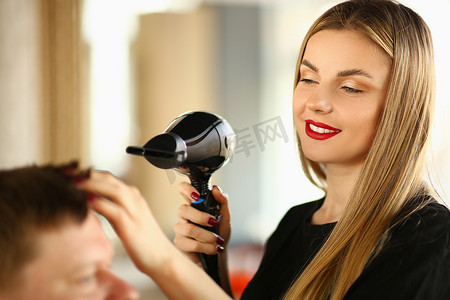 男人吹头发摄影照片_女理发师用吹风机给男人做造型