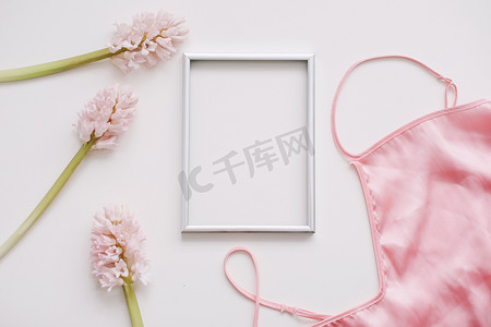 相框标题摄影照片_空白相框、丝绸内衣和白色背景上的粉红色花朵。