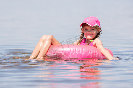 游泳画面摄影照片_戴帽子的女孩在河里游泳，坐在腿上游泳，看着画面